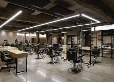 Modern interior of HAIR ETC. Studio in Nicosia, CY featuring sleek black salon chairs and elegant lighting.