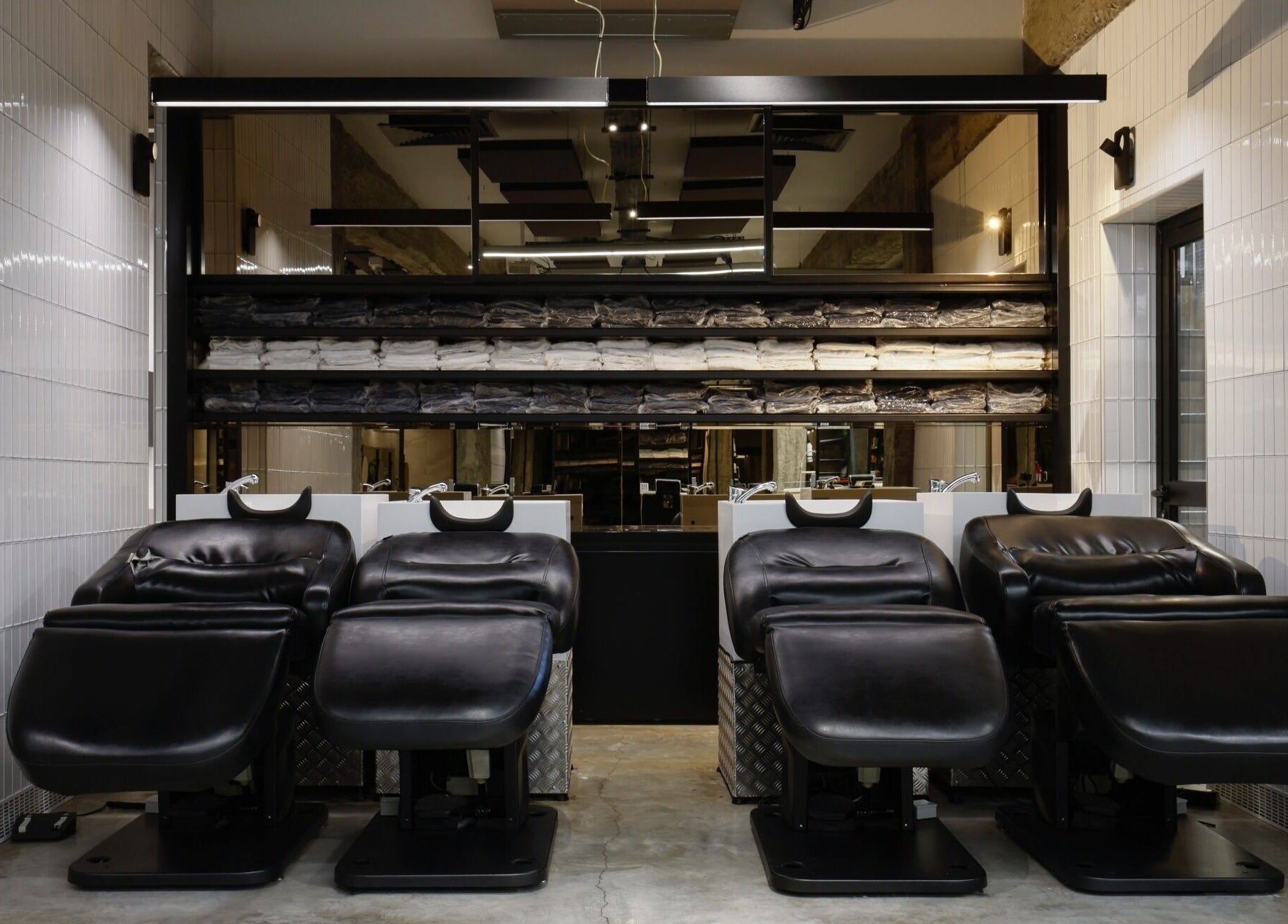 Elegant shampoo chairs at HAIR ETC. Studio, Nicosia, CY, with neatly arranged towels in the background.