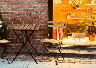 Cozy outdoor seating at David Nukri salon, Frederiksberg, Denmark, DK next to warm lit window display.