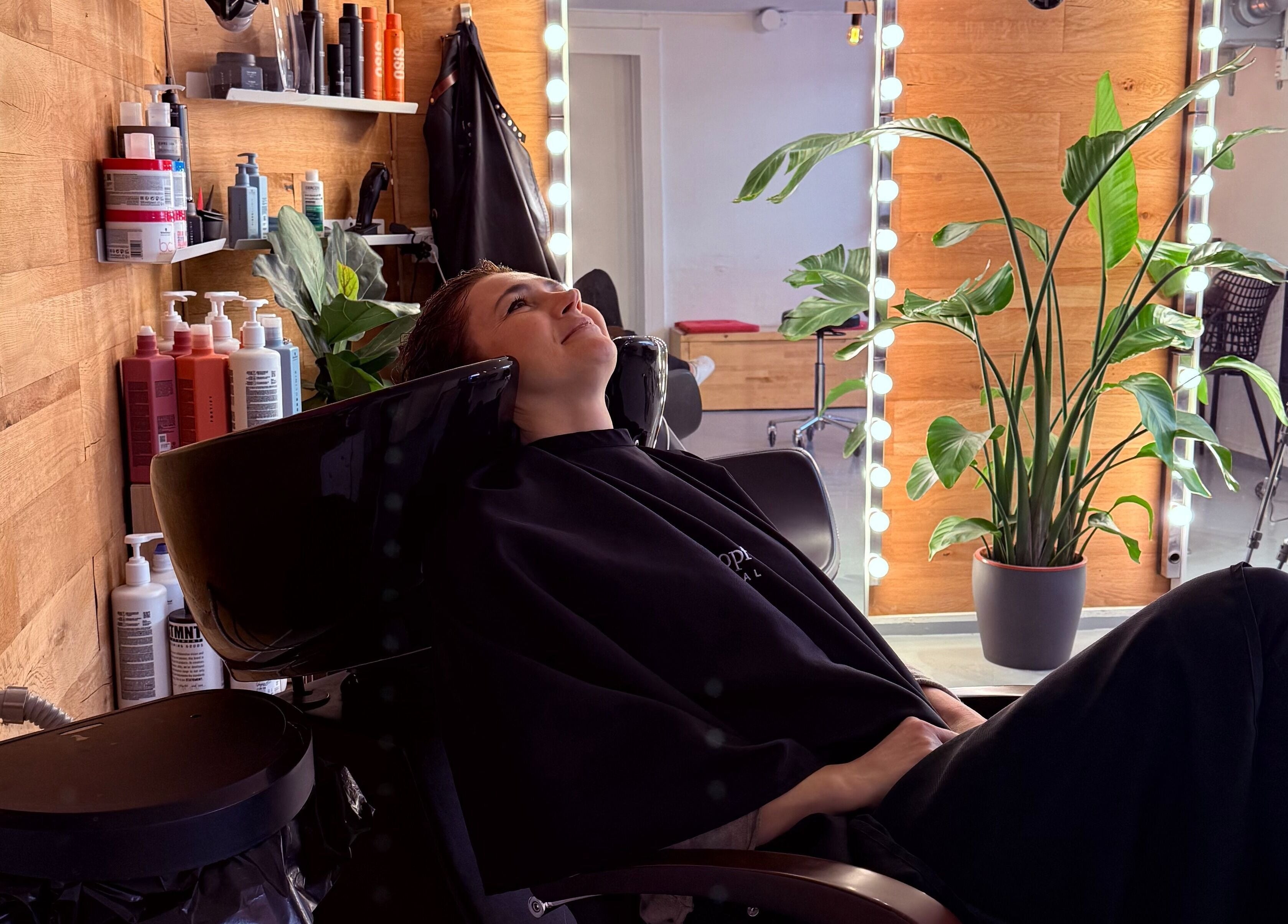 Client enjoying a hair wash at David Nukri, Frederiksberg, Denmark, DK with lush plants and elegant decor.