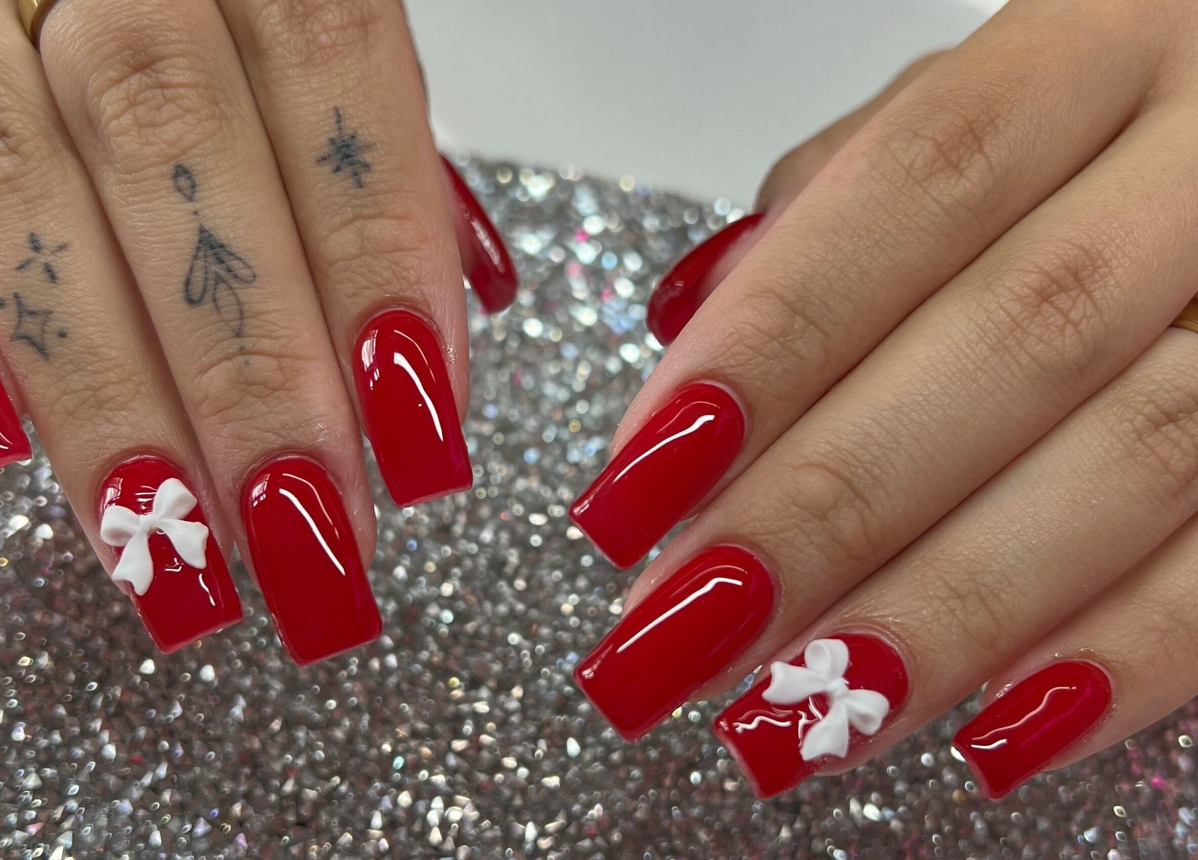 Elegant red nails with white bows at Pink Sphinx Nails, Binbrook, Ontario, CA.