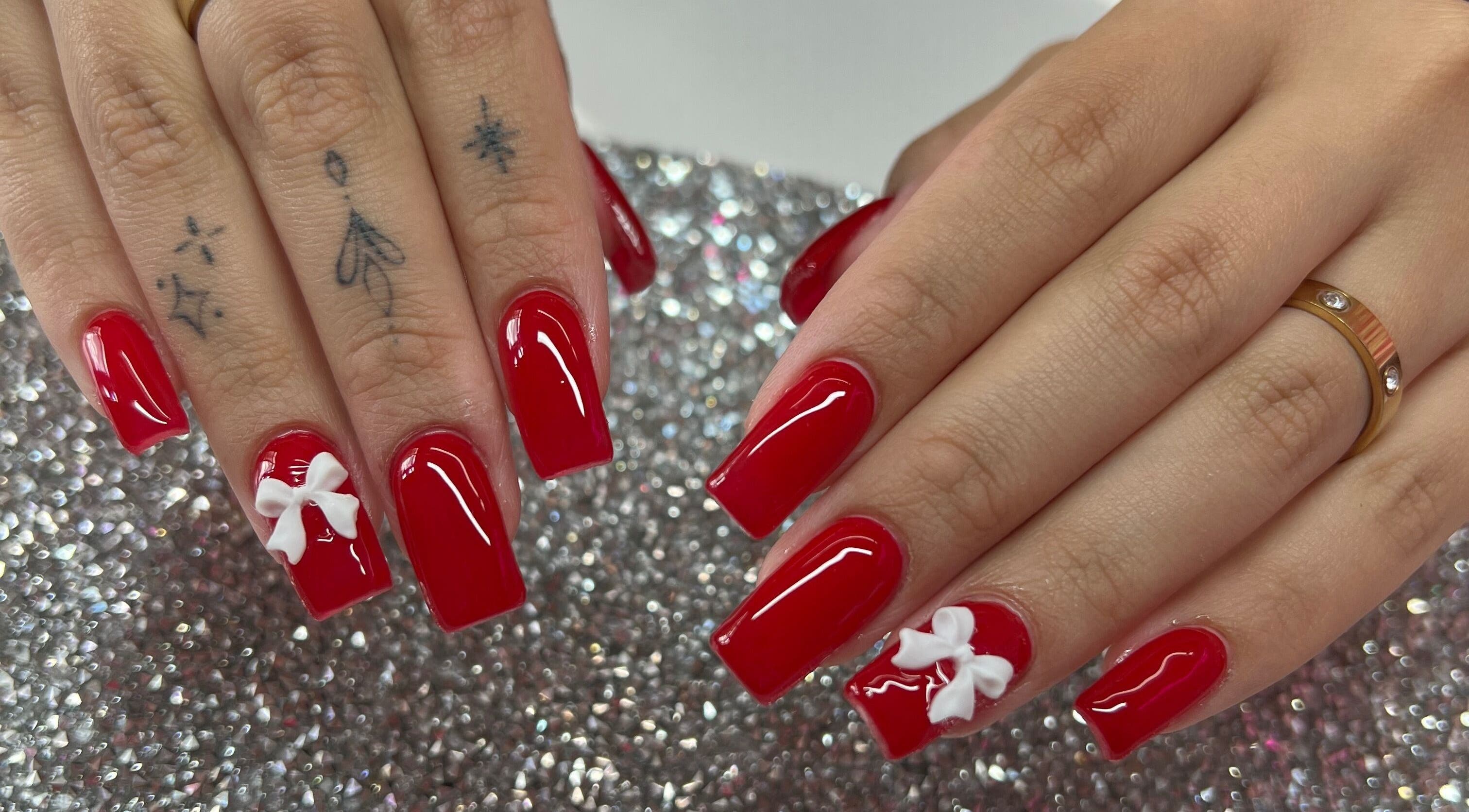 Elegant red nails with white bows at Pink Sphinx Nails, Binbrook, Ontario, CA.