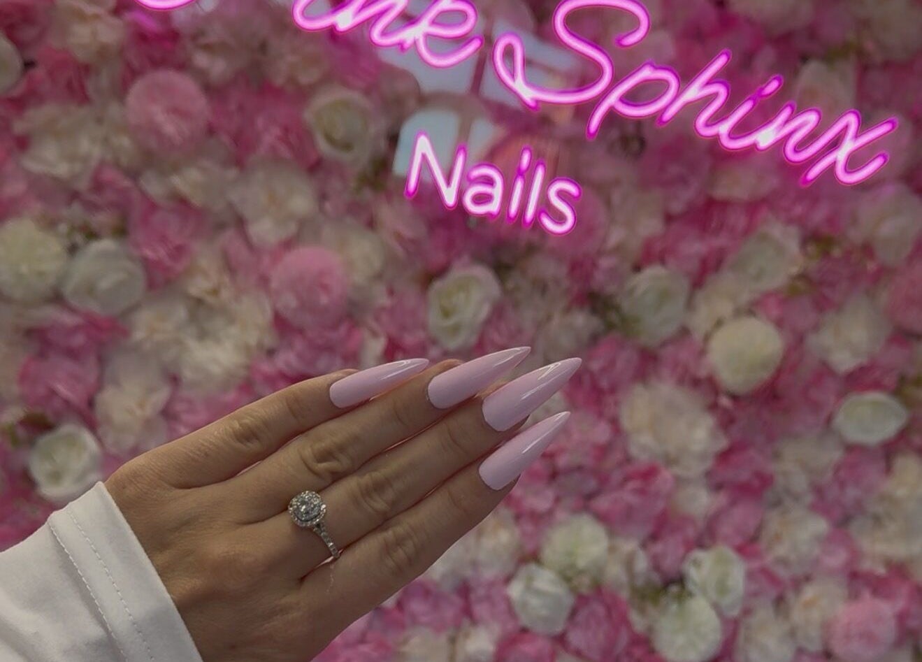 Elegant pink nails at Pink Sphinx Nails, Binbrook, Ontario, CA, showcased against a floral background.