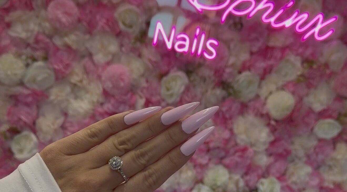Elegant pink nails at Pink Sphinx Nails, Binbrook, Ontario, CA, showcased against a floral background.