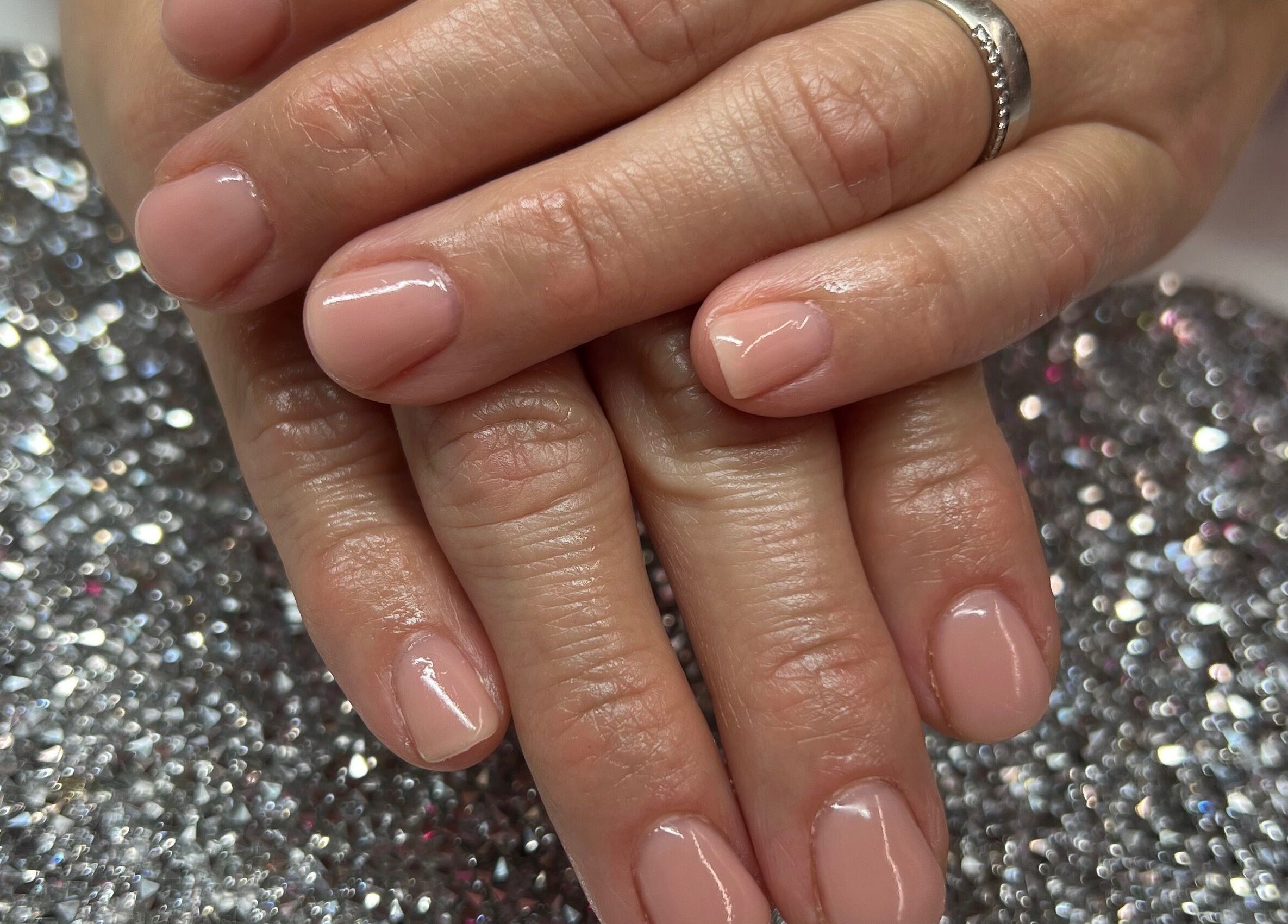 Beautiful pink manicure at Pink Sphinx Nails, Binbrook, Ontario, CA. Perfectly polished hand on a sparkly background.