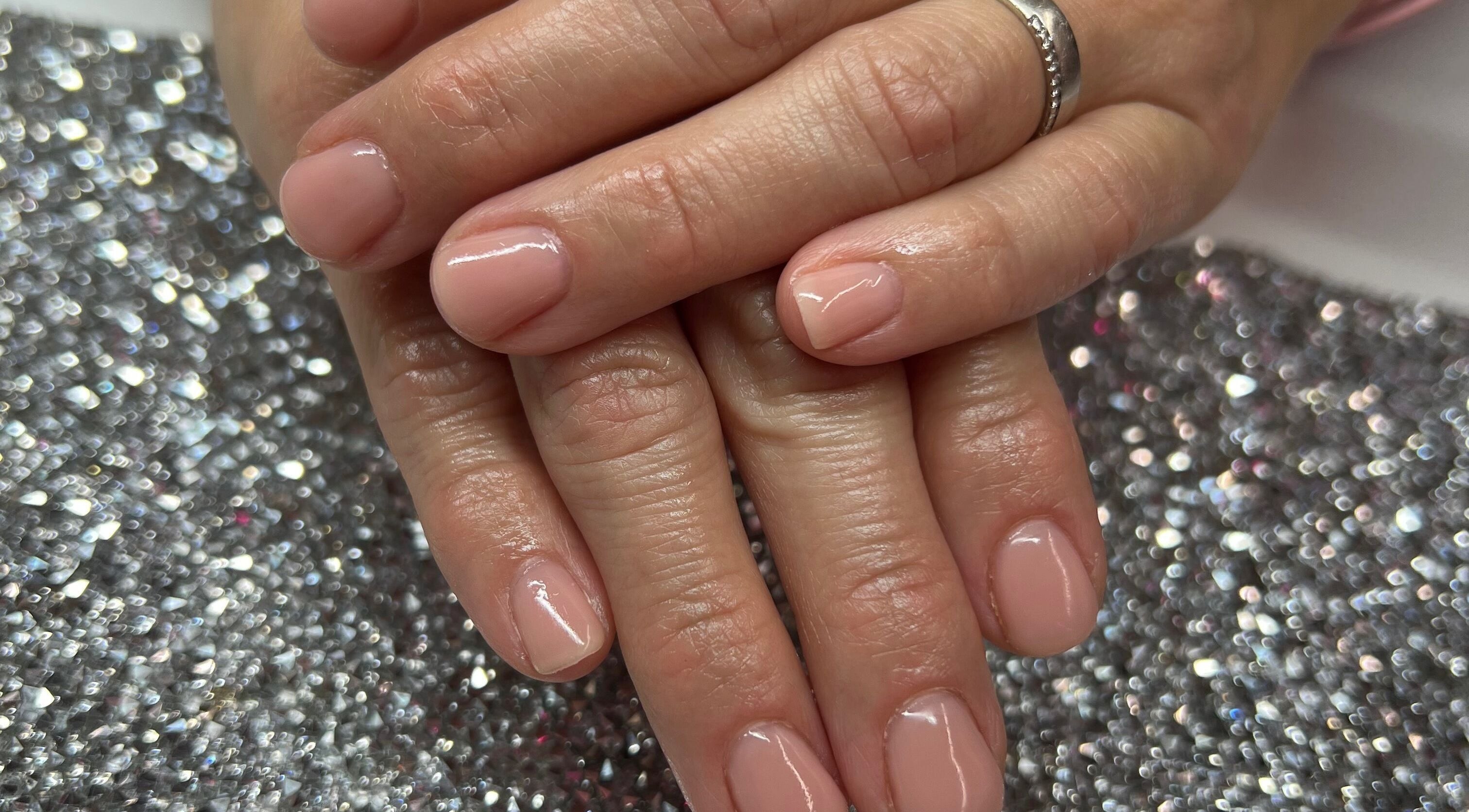 Beautiful pink manicure at Pink Sphinx Nails, Binbrook, Ontario, CA. Perfectly polished hand on a sparkly background.