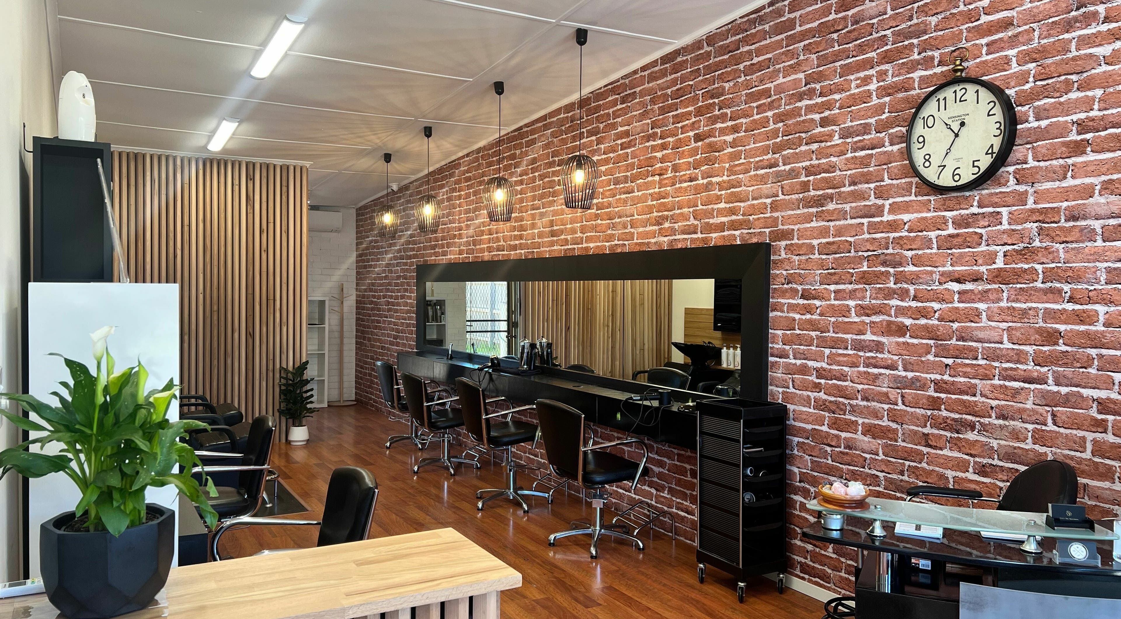 Modern interior of Hair by Karmen in Rosebud, Victoria, AU with stylish chairs and brick wall design.