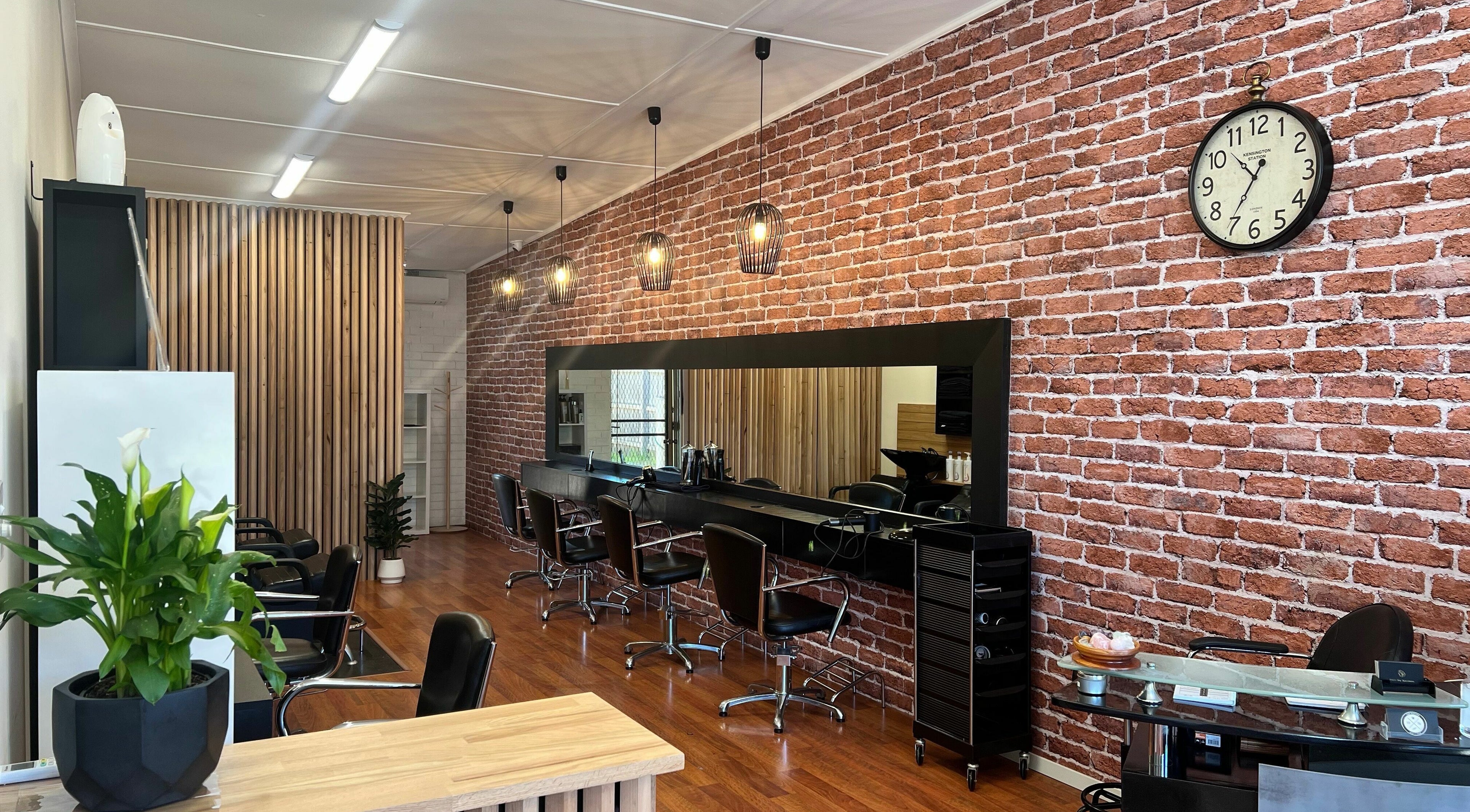 Modern interior of Hair by Karmen in Rosebud, Victoria, AU with stylish chairs and brick wall design.