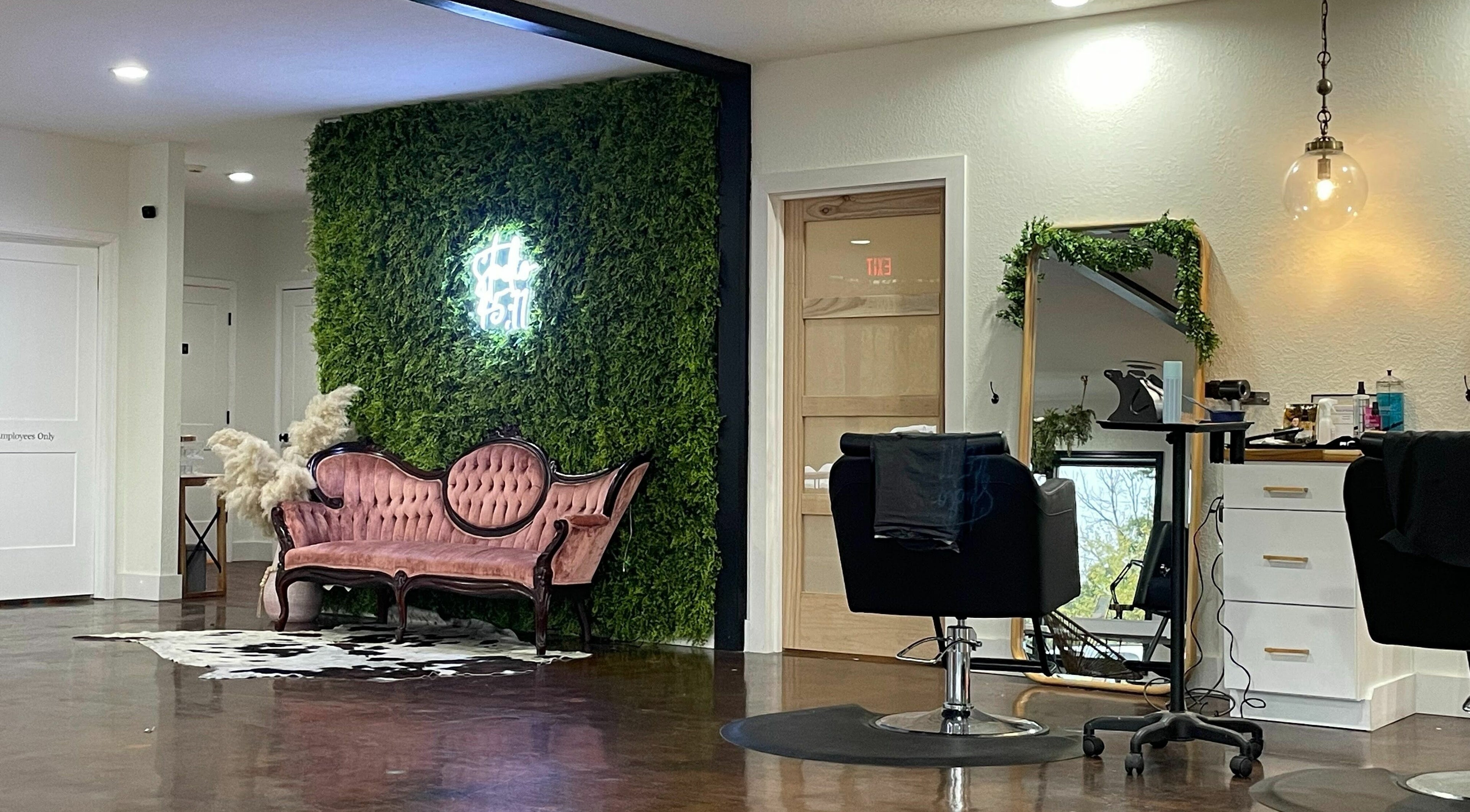 Chic interior of Studio 45:11 Salon in Seymour, Tennessee, US with a vintage sofa and green wall.