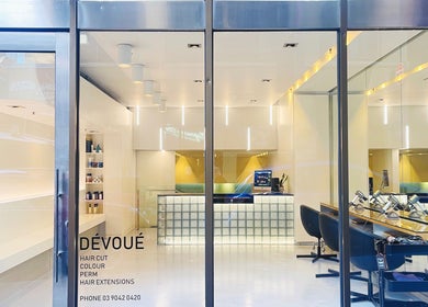 Modern interior of Devoue Hair in Melbourne, Victoria, AU with sleek styling stations and illuminated reception.