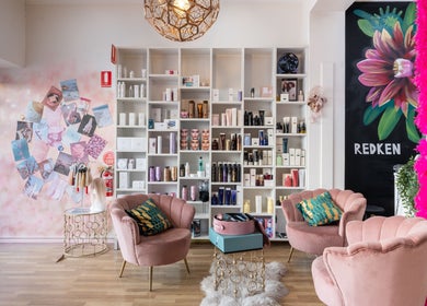 Elegant salon interior at M.O.H & Co, Melbourne, Victoria, AU, with plush pink chairs and beauty products display.