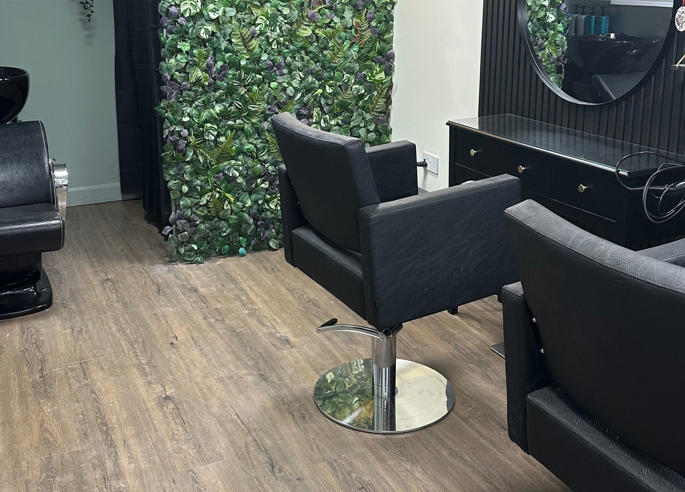 Modern salon interior with leafy wall at Envious Salon, Crawley, England, GB.