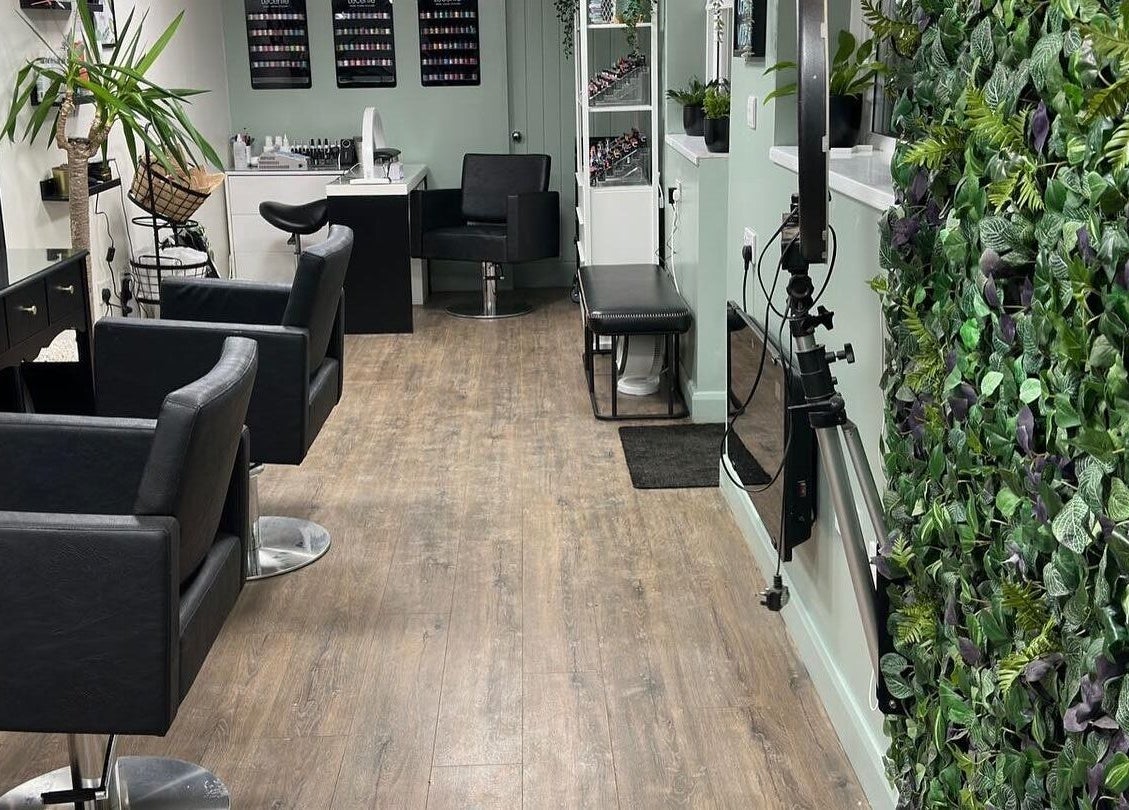 Elegant interior of Envious Salon in Crawley, England with plush chairs and a vibrant plant wall.