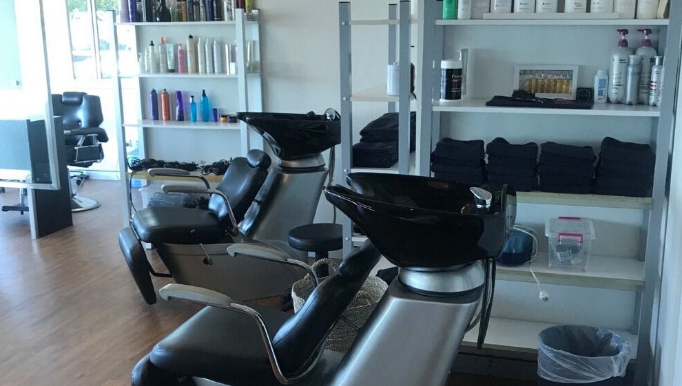 Stylish washing stations at Studio Vogue Salon in Baringa, Queensland, AU, featuring sleek black chairs and shelves.