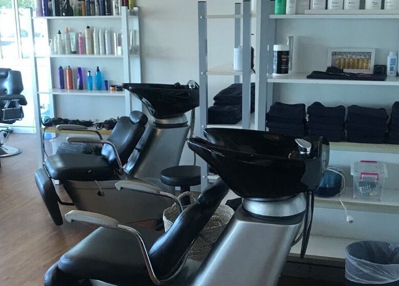 Stylish washing stations at Studio Vogue Salon in Baringa, Queensland, AU, featuring sleek black chairs and shelves.