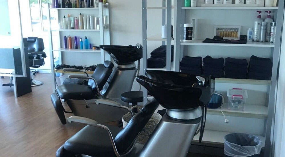 Stylish washing stations at Studio Vogue Salon in Baringa, Queensland, AU, featuring sleek black chairs and shelves.