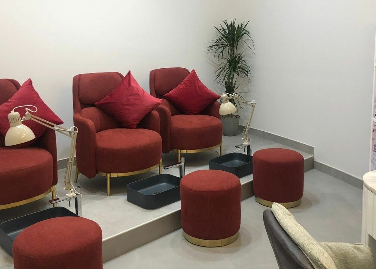 Cozy pedicure area with red seats at Ok Beauty Salon, دبي, دبي, AE, offering a stylish and relaxing environment.