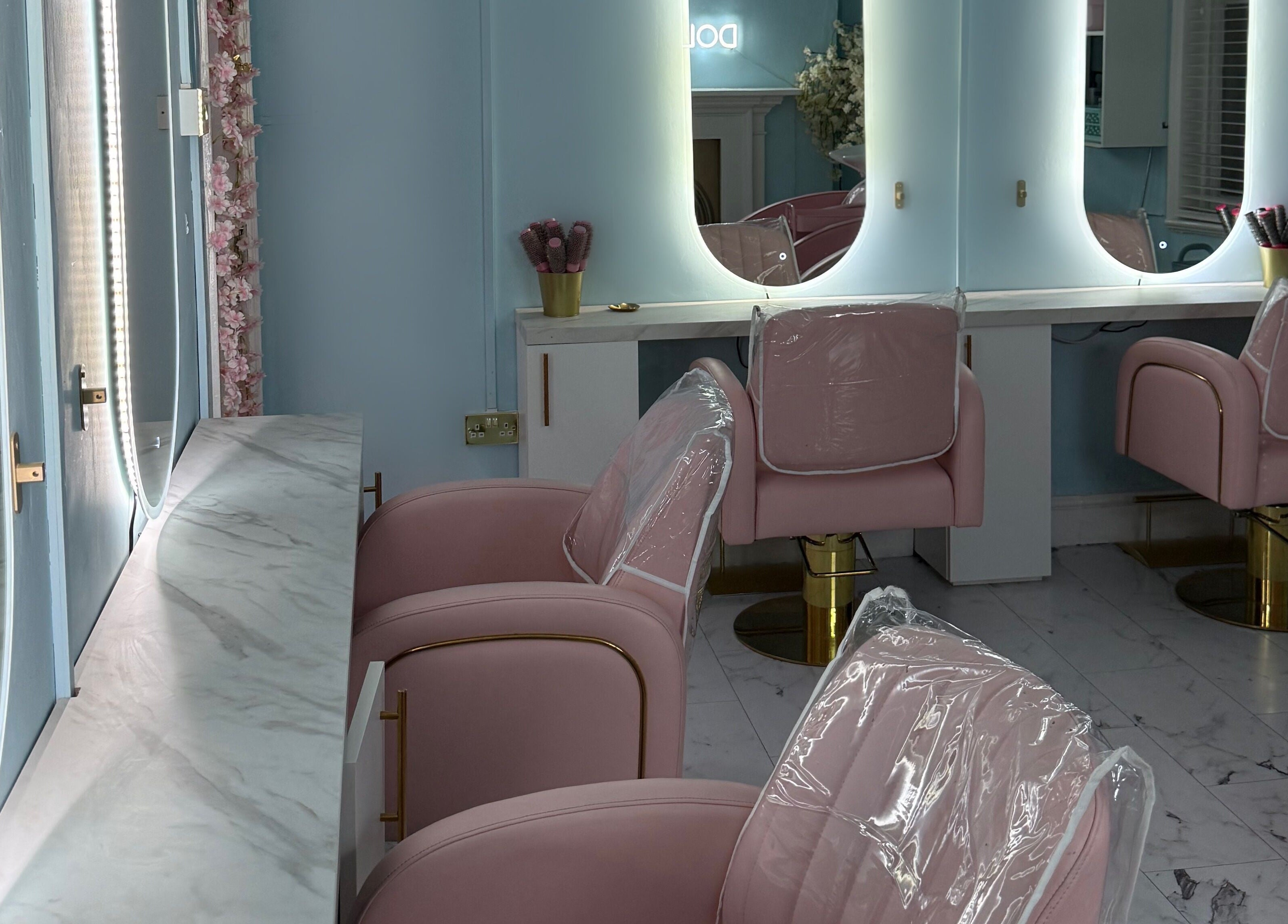 Elegant salon interior at The Doll House York, featuring plush pink chairs and stylish mirrors, York, England, GB.