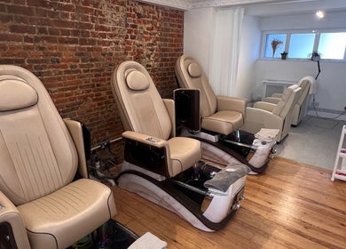 Luxurious massage chairs at TLC Beauty Studio, Chichester, England, GB, set against a rustic brick wall.