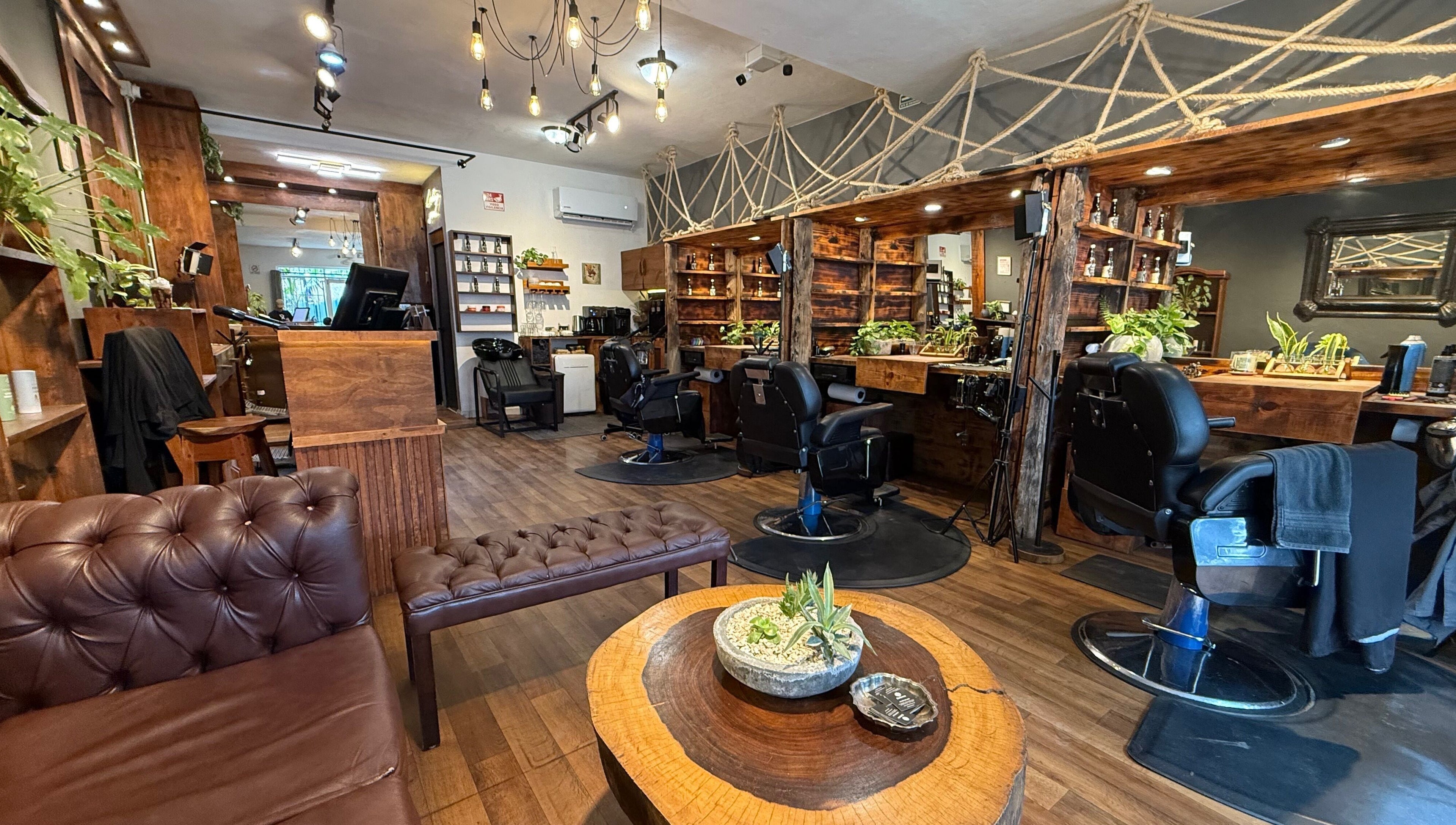 Interior moderno de Barberos Tulum - Av. Kukulkán con sillas de barbero y decoración rústica. Tulum, Quintana Roo, MX.