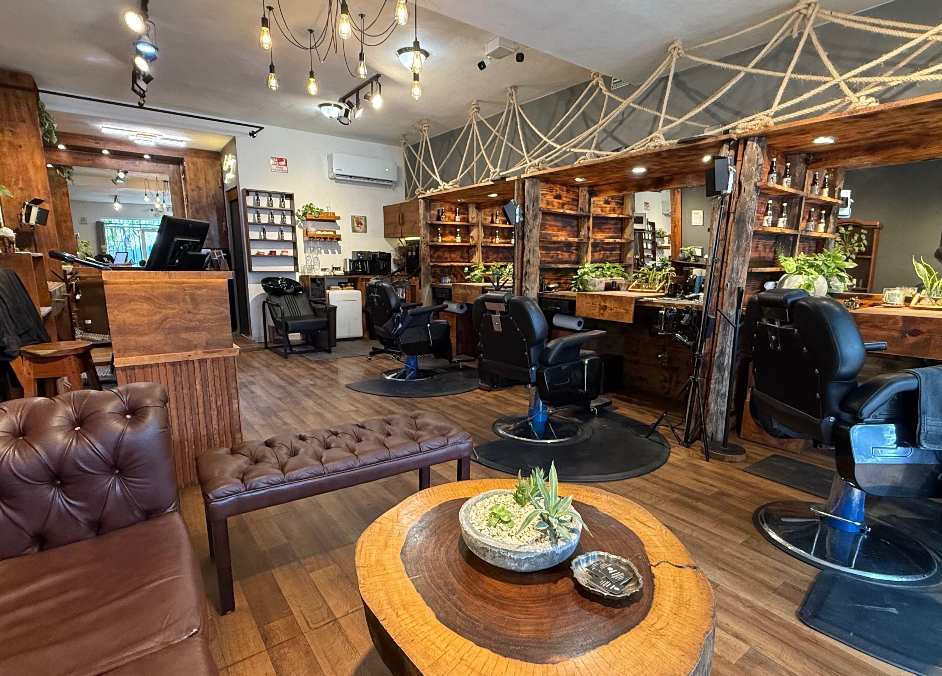 Interior moderno de Barberos Tulum - Av. Kukulkán con sillas de barbero y decoración rústica. Tulum, Quintana Roo, MX.