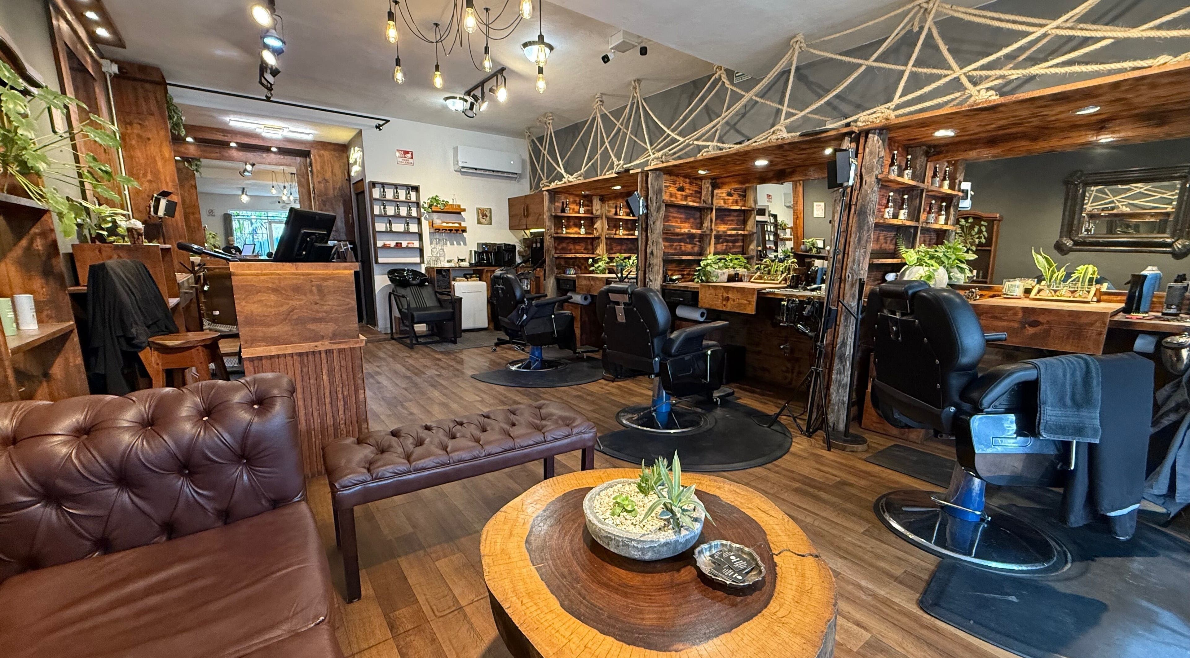 Interior moderno de Barberos Tulum - Av. Kukulkán con sillas de barbero y decoración rústica. Tulum, Quintana Roo, MX.