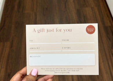 Gift card from Brown Sugar Rozelle, Rozelle, New South Wales, AU held by a hand over a wooden floor.