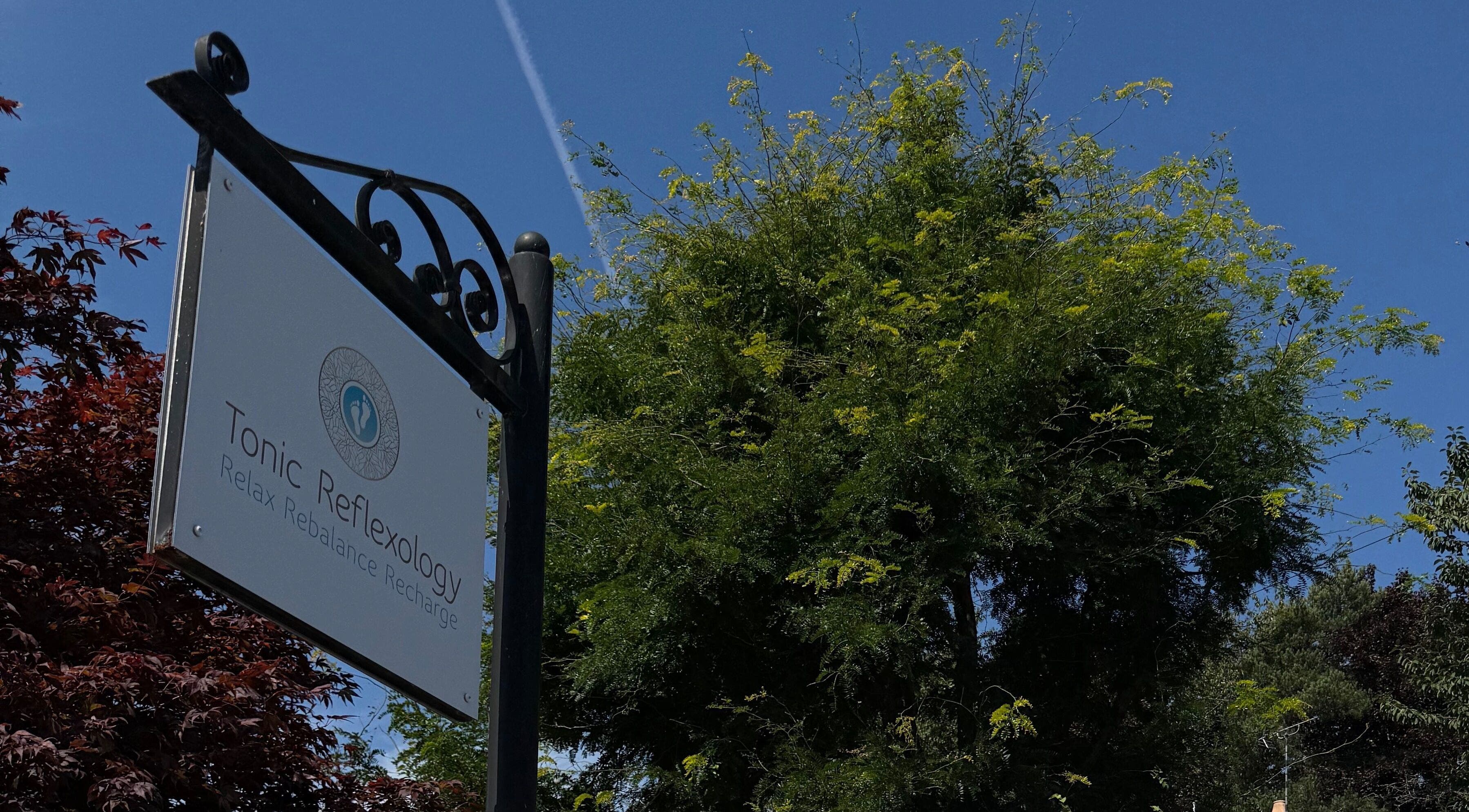 Tonic Reflexology sign amidst greenery and blue sky, Derby, England, GB.
