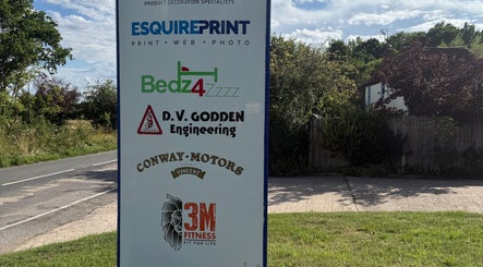 Signboard displaying various business logos, including Indigo Massage at 3M Fitness, Nettlestead, GB.
