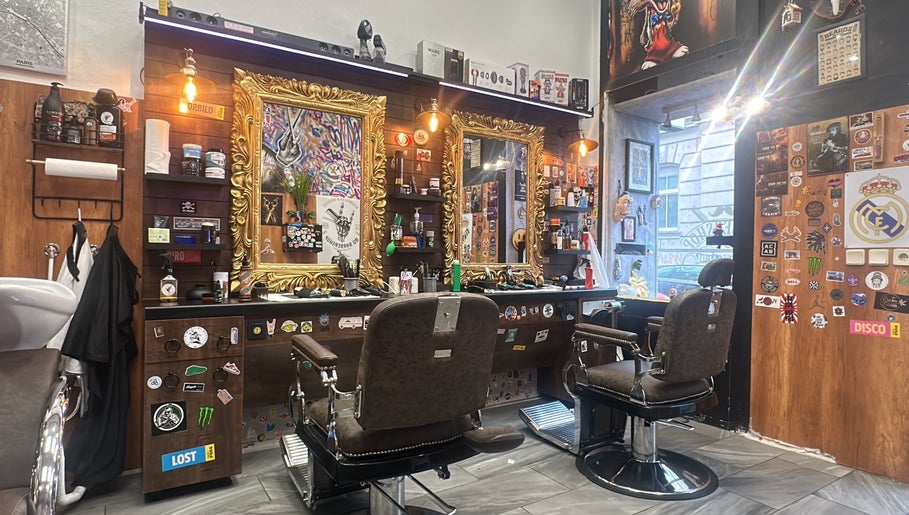 Innenansicht von Mo Barbershop in Wien, Wien, AT mit goldenen Spiegeln und stilvollen Friseurstühlen.