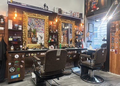Innenansicht von Mo Barbershop in Wien, Wien, AT mit goldenen Spiegeln und stilvollen Friseurstühlen.