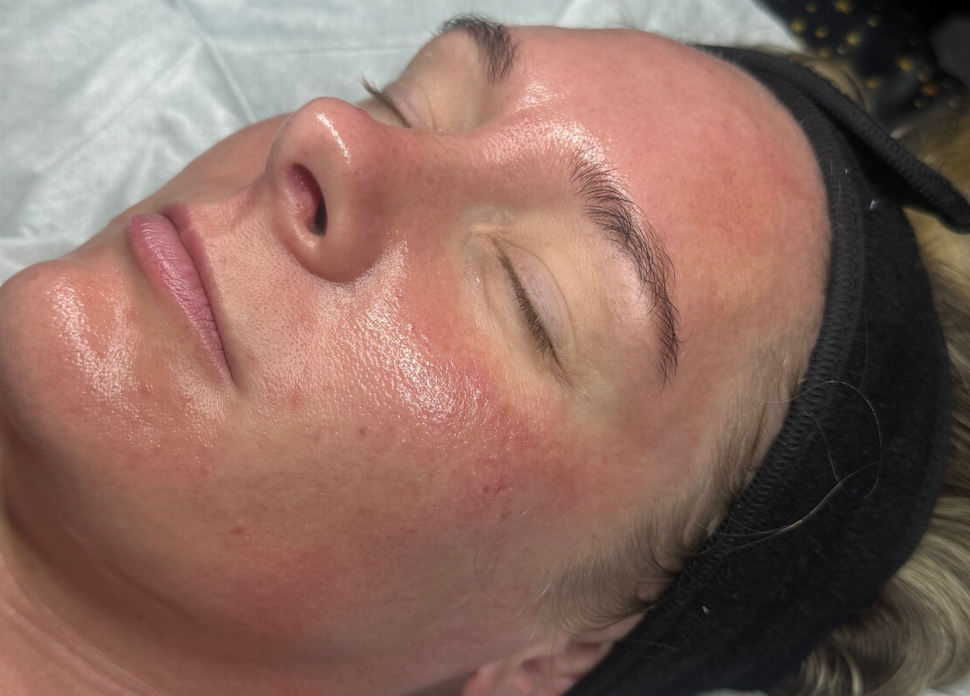 Relaxed woman with glowing skin during facial treatment at Chlos Beauty Corner, Callington, England, GB.