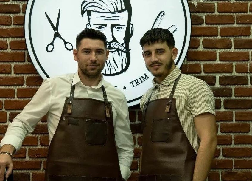 Frizerii de la HiStory Barbershop Camil Ressu 8, București, București, RO, purtând șorțuri maro.