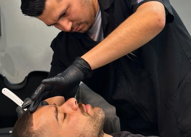 Barbero realizando afeitado preciso en Barbería Boss Perla, Tijuana, Baja California, MX.