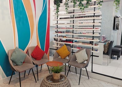 Seating area at Polish Nails Care & More Salon in Abu Dhabi, AE with a vibrant wall and nail polish display.