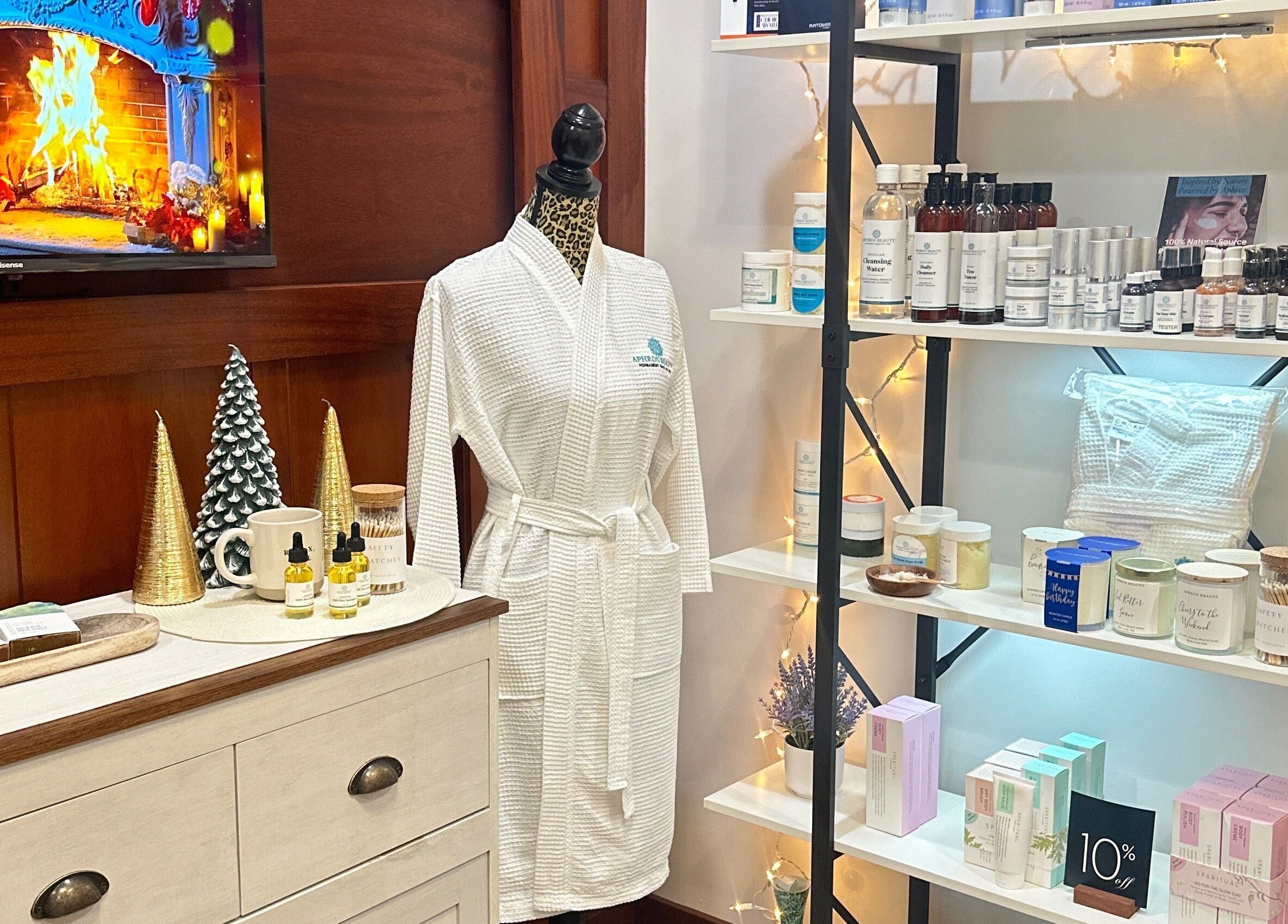 Aphros Beauty display with robe and products in Homewood, Alabama, US, beside a warm virtual fireplace.