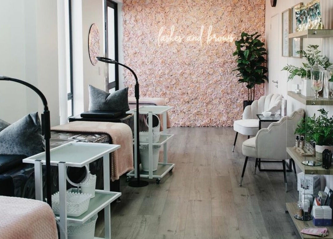 Chic interior of The Brow Specialist in Somerset West, Western Cape, ZA with plush seating and floral wall.