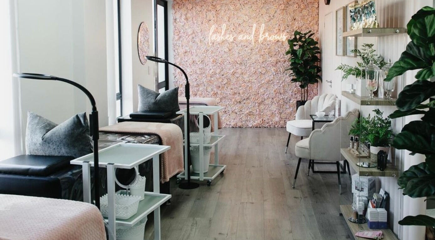 Chic interior of The Brow Specialist in Somerset West, Western Cape, ZA with plush seating and floral wall.