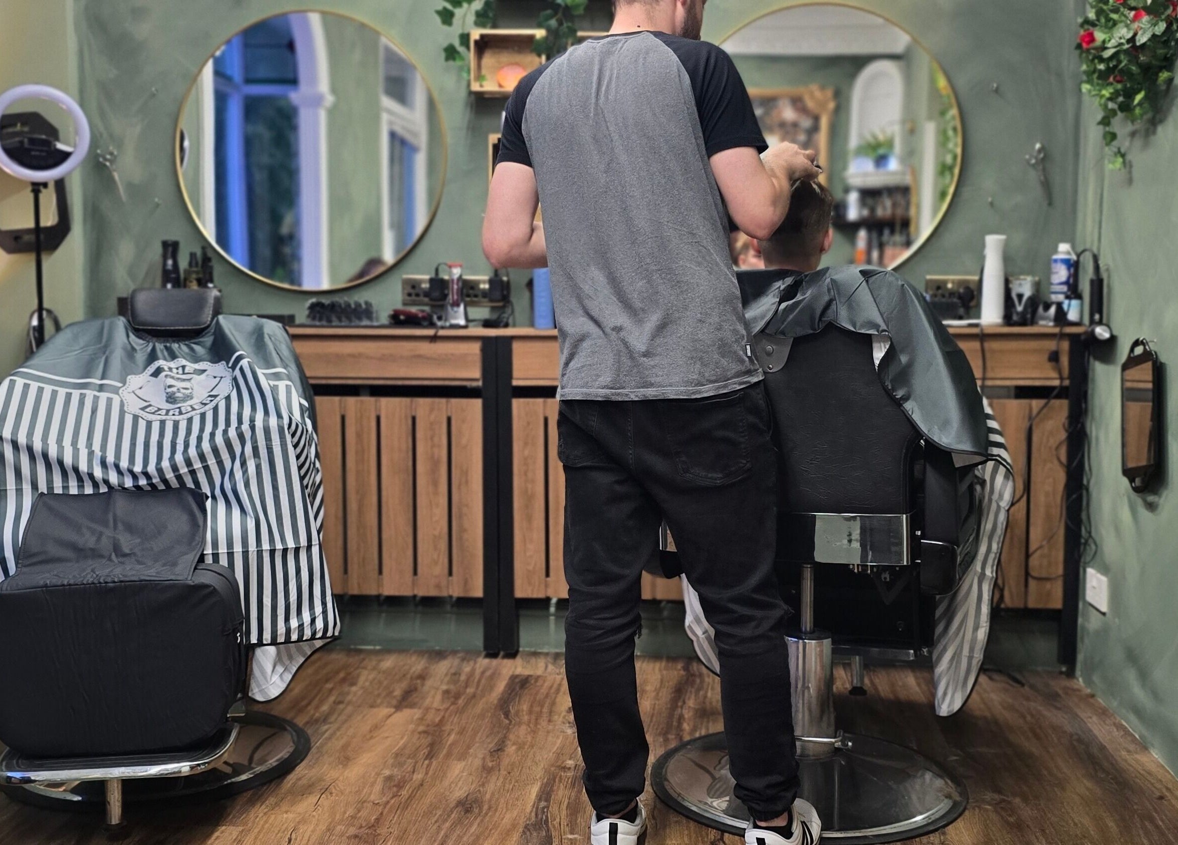 Interior view of The LadyBarber’s Shop in New Bradwell, England, featuring a barber working on a client.