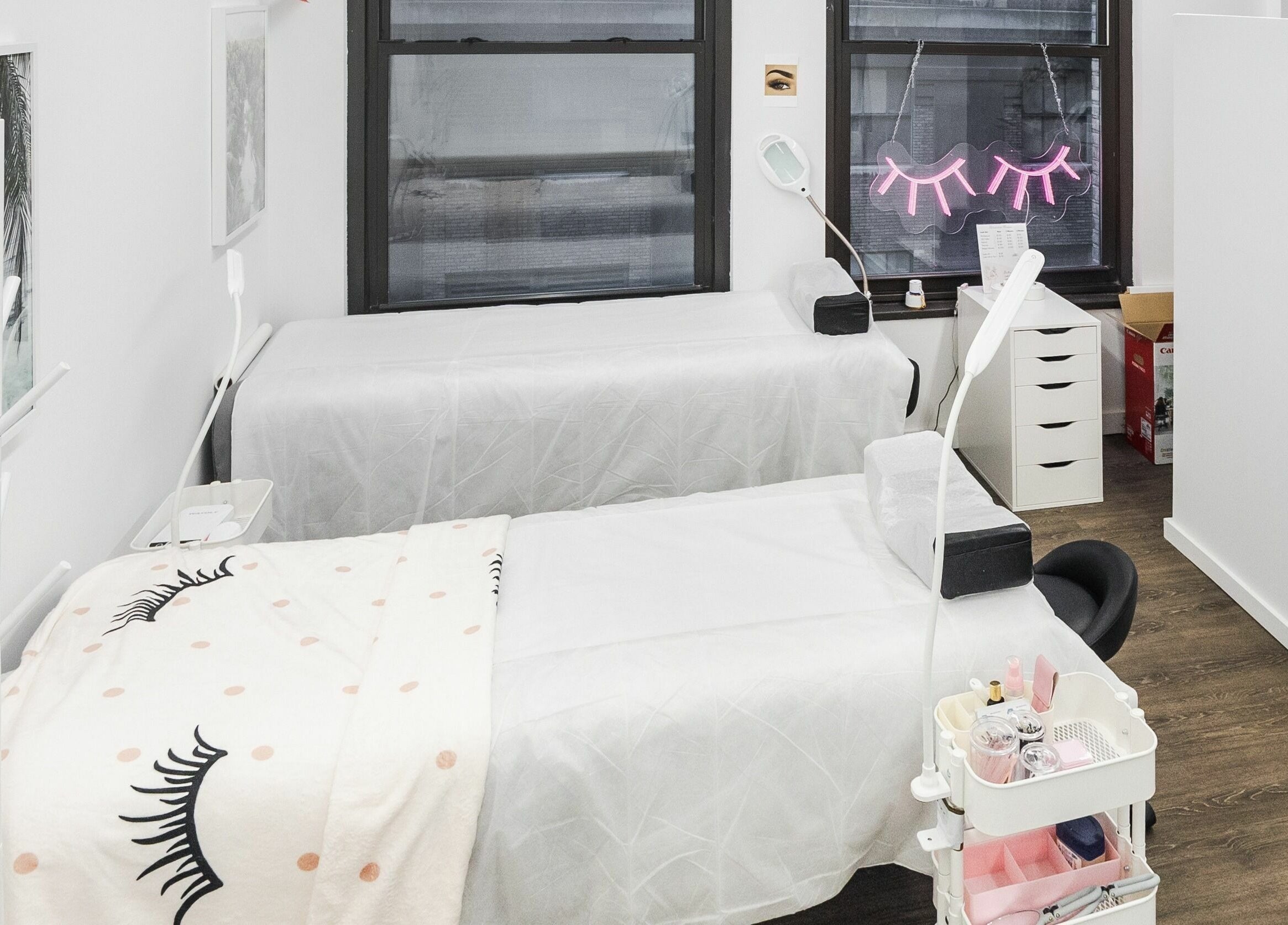 Cozy treatment room at V Lash Studio, New York, New York, US, featuring two beds with lash-themed decor.