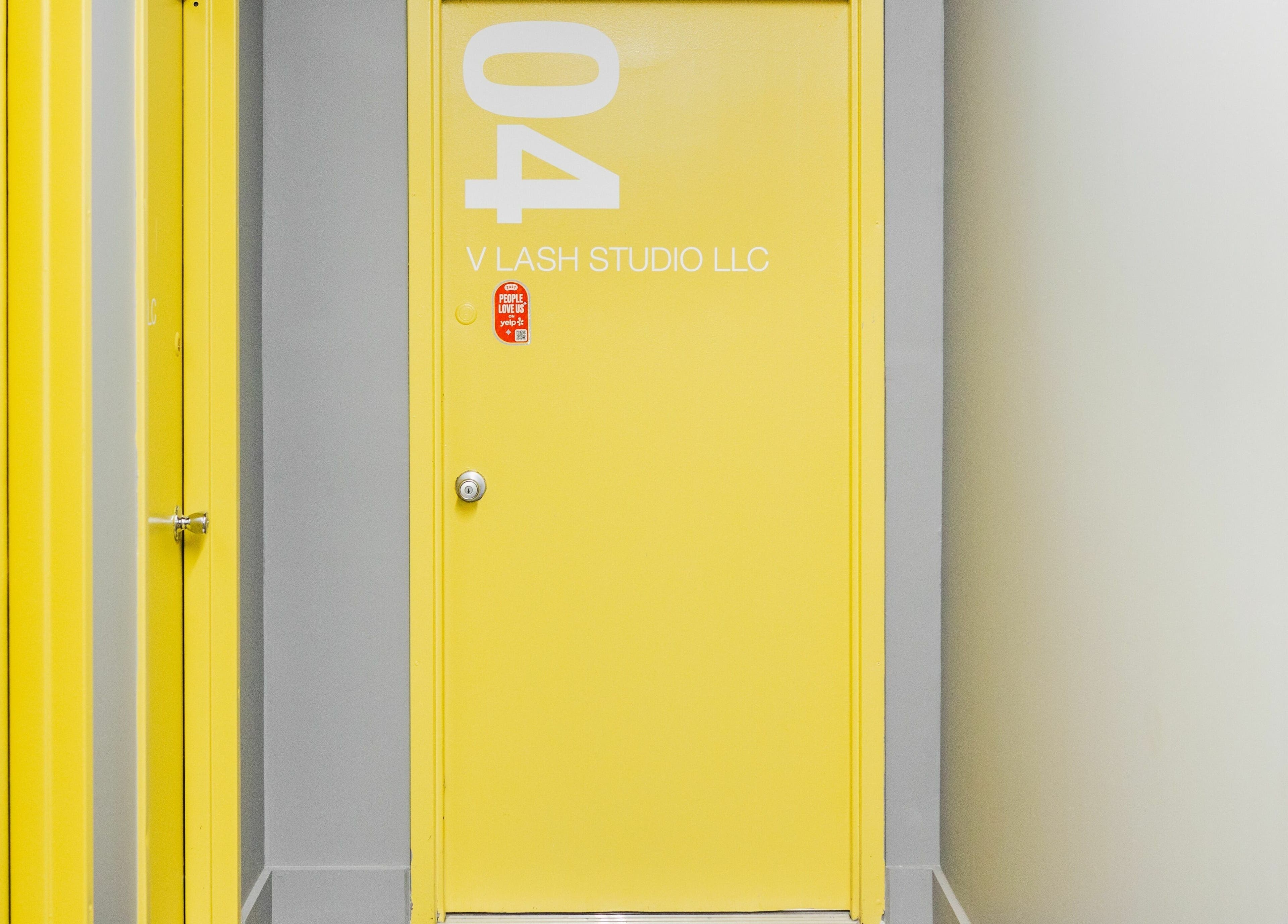 Bright yellow door at V Lash Studio, New York, New York, US, welcoming guests with vibrant elegance.
