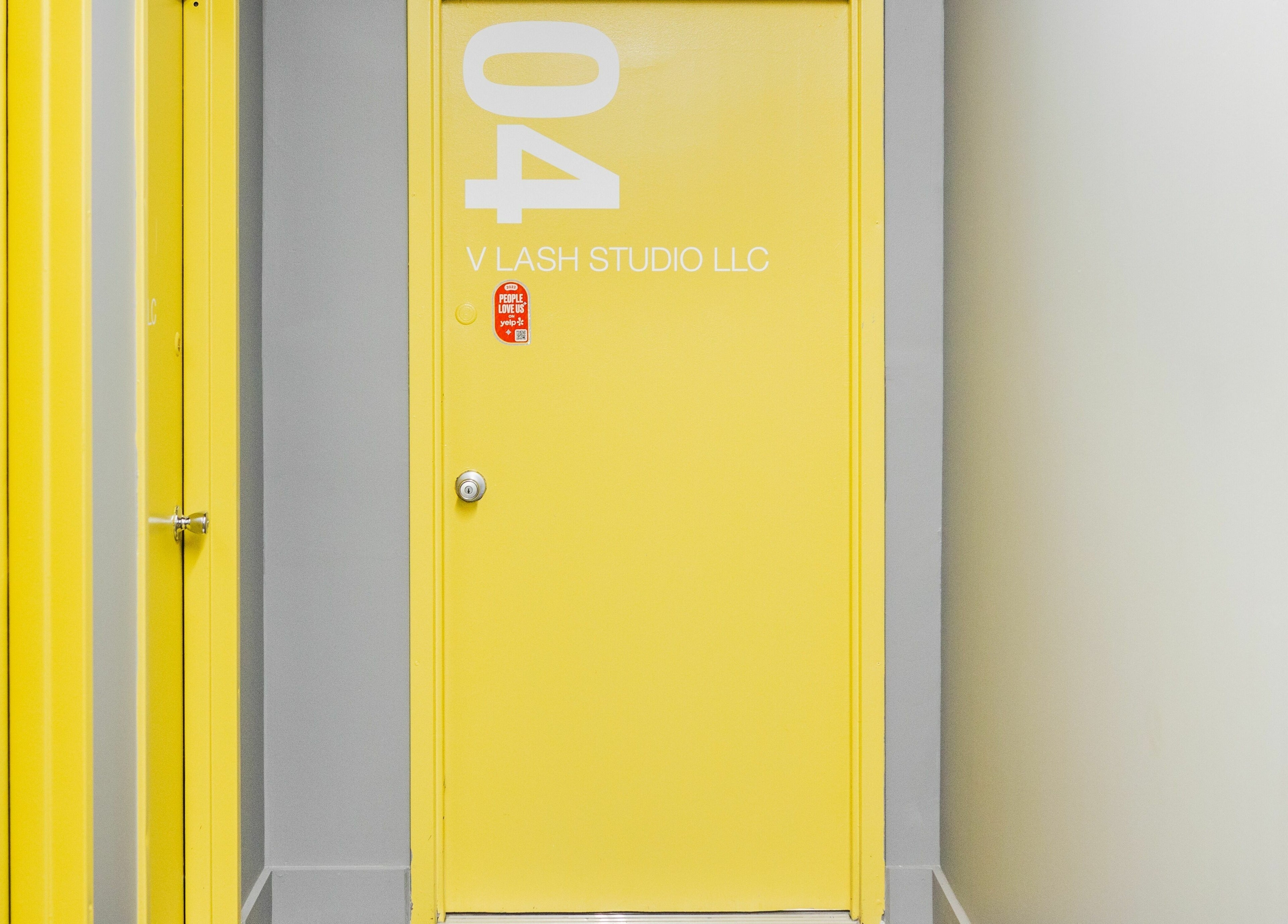 Bright yellow door at V Lash Studio, New York, New York, US, welcoming guests with vibrant elegance.