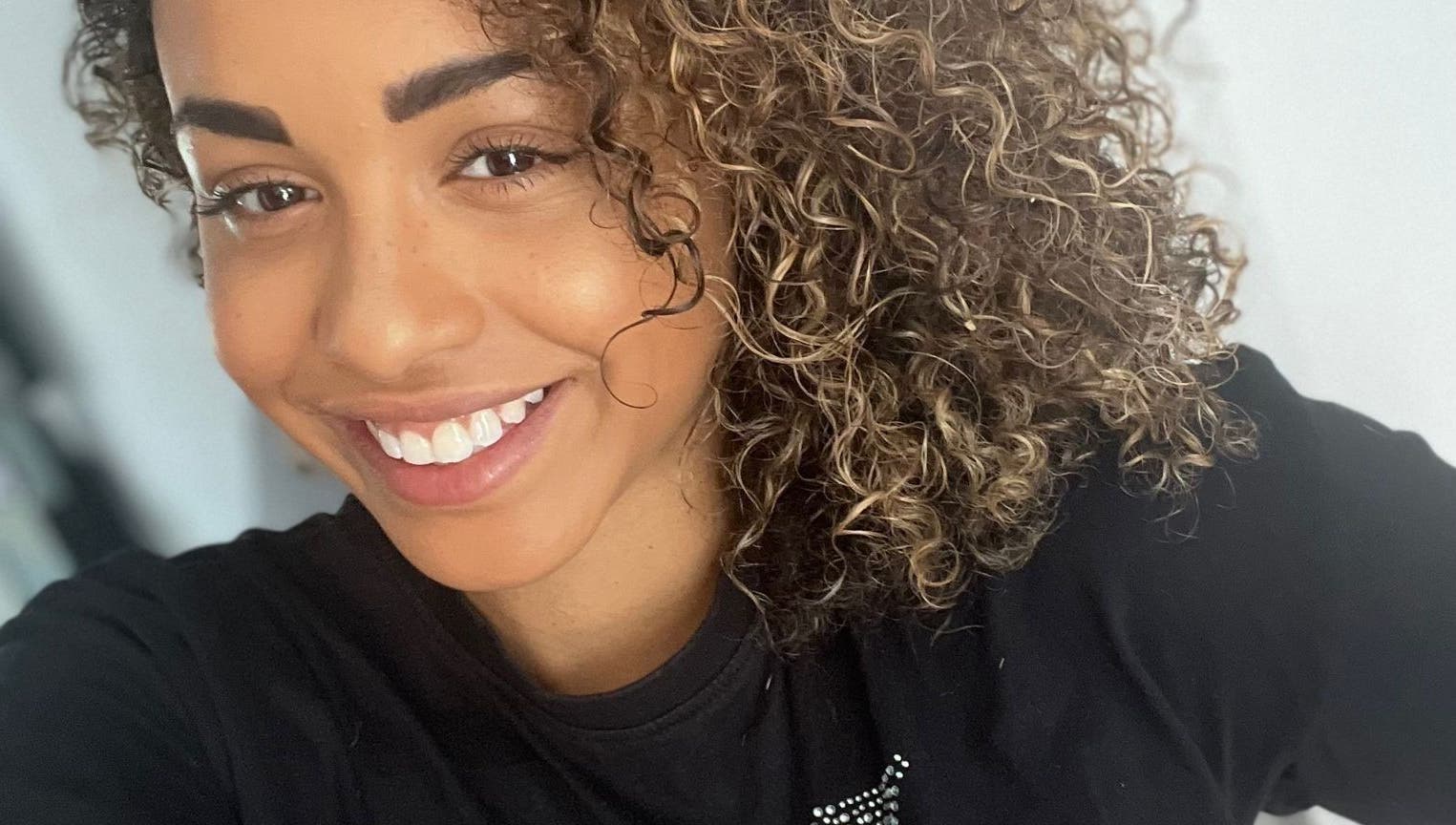 Smiling woman with curly hair at Manes by Morgan in Willenhall, England, GB.