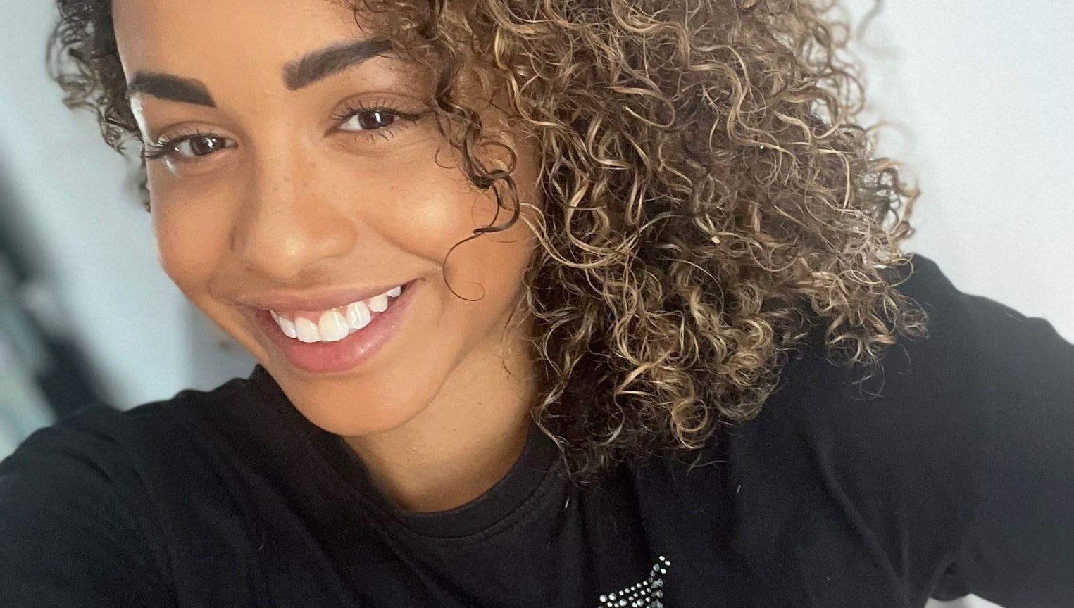 Smiling woman with curly hair at Manes by Morgan in Willenhall, England, GB.