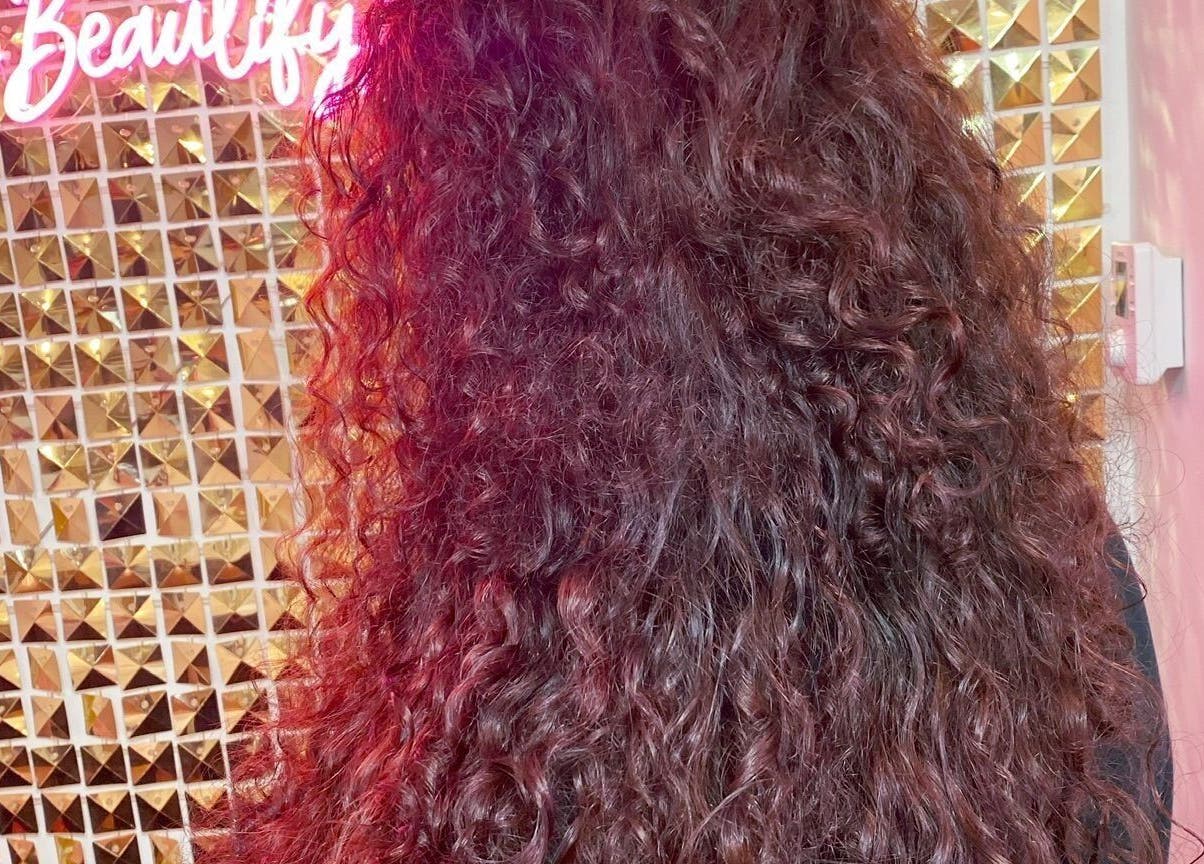 Vibrant curly hairstyle at Manes by Morgan, Willenhall, England, GB. Glamorous golden backdrop enhances beauty.