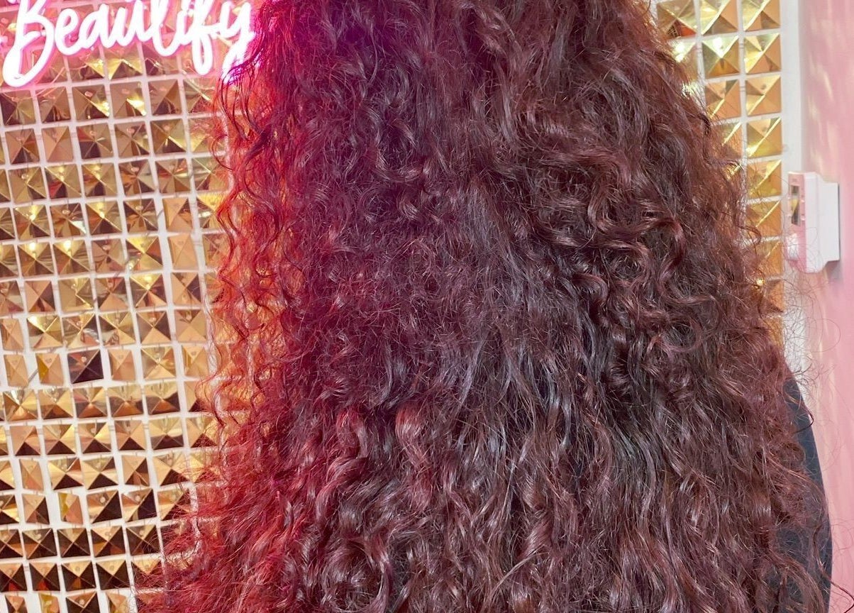Vibrant curly hairstyle at Manes by Morgan, Willenhall, England, GB. Glamorous golden backdrop enhances beauty.