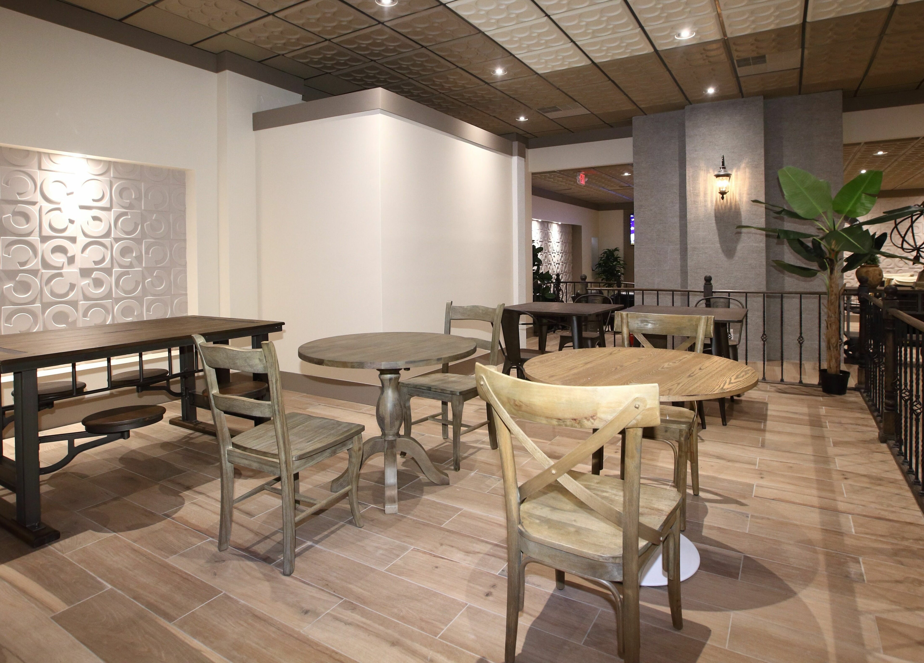 Elegant seating area at Aria Spa in Butler, New Jersey, US, featuring wooden tables and chairs with lush plants.