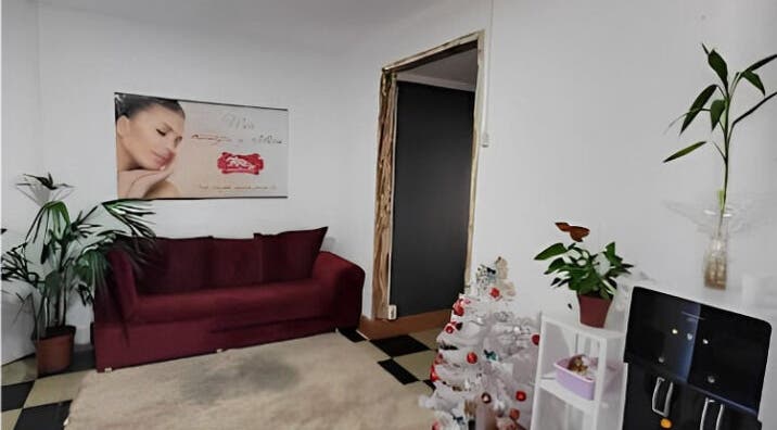 Elegante sala de espera en MIA Estética, Salto, Departamento De Salto, UY, con sofá burdeos y decoración moderna.