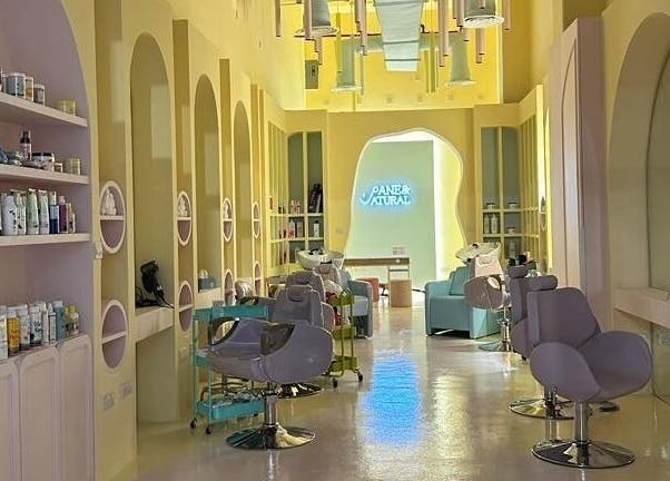 Modern salon interior at ManeandNatural | كيرلي بوتيك - Riyadh Branch, Riyadh, SA, with stylish chairs and shelves.