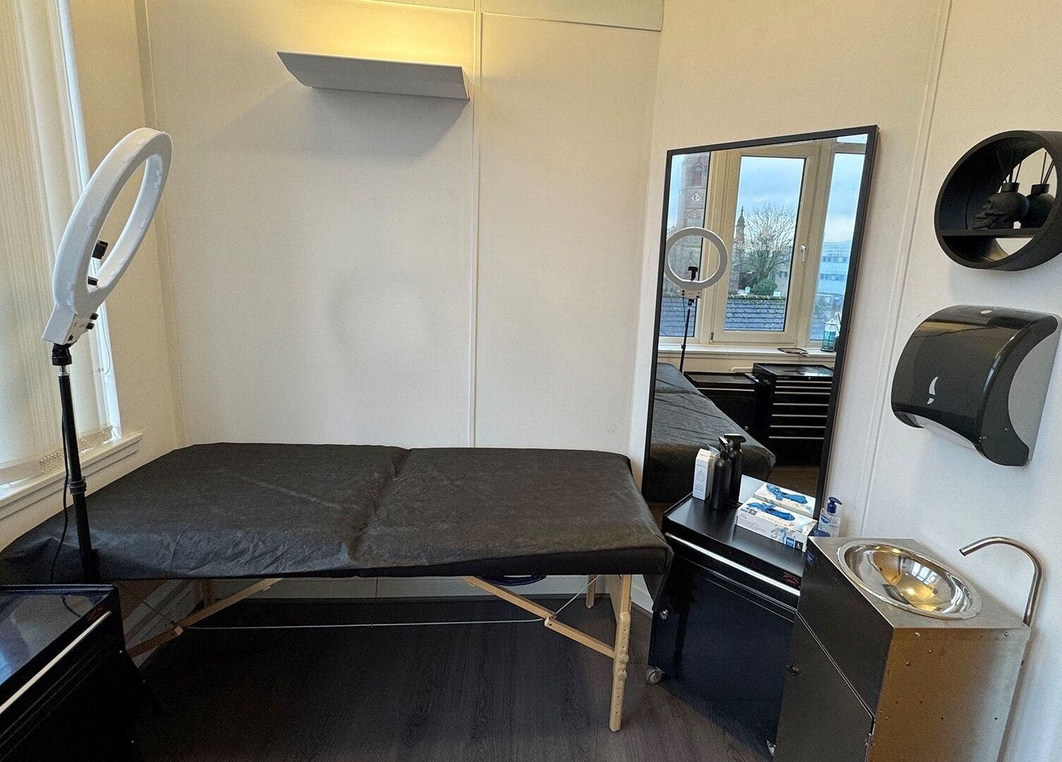 Modern interior of Valhalla Tattoo Studio, Kilmarnock, Scotland, GB, featuring a black treatment bed and ring light.